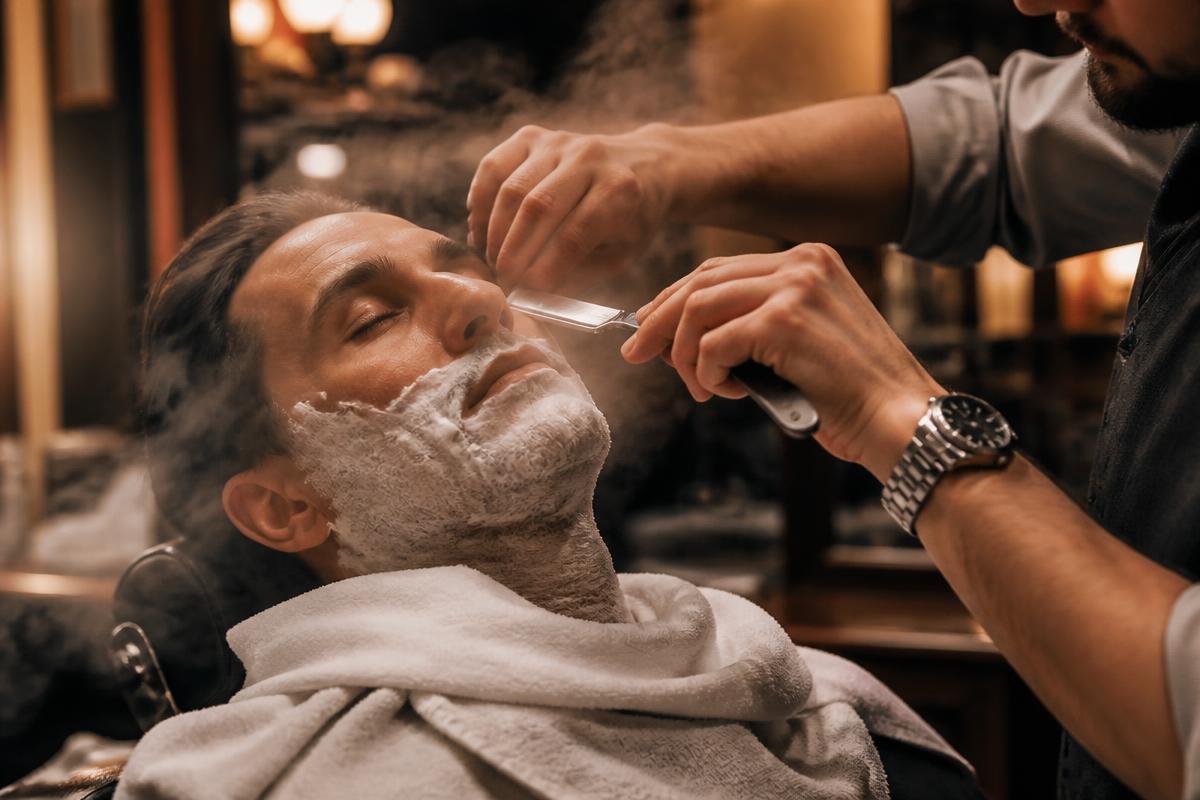 Hot towel straight razor shave with steam rising in a warm barbershop
